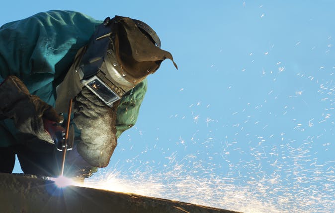Technician welding a steel HVAC component on a job site near Fort Worth, TX